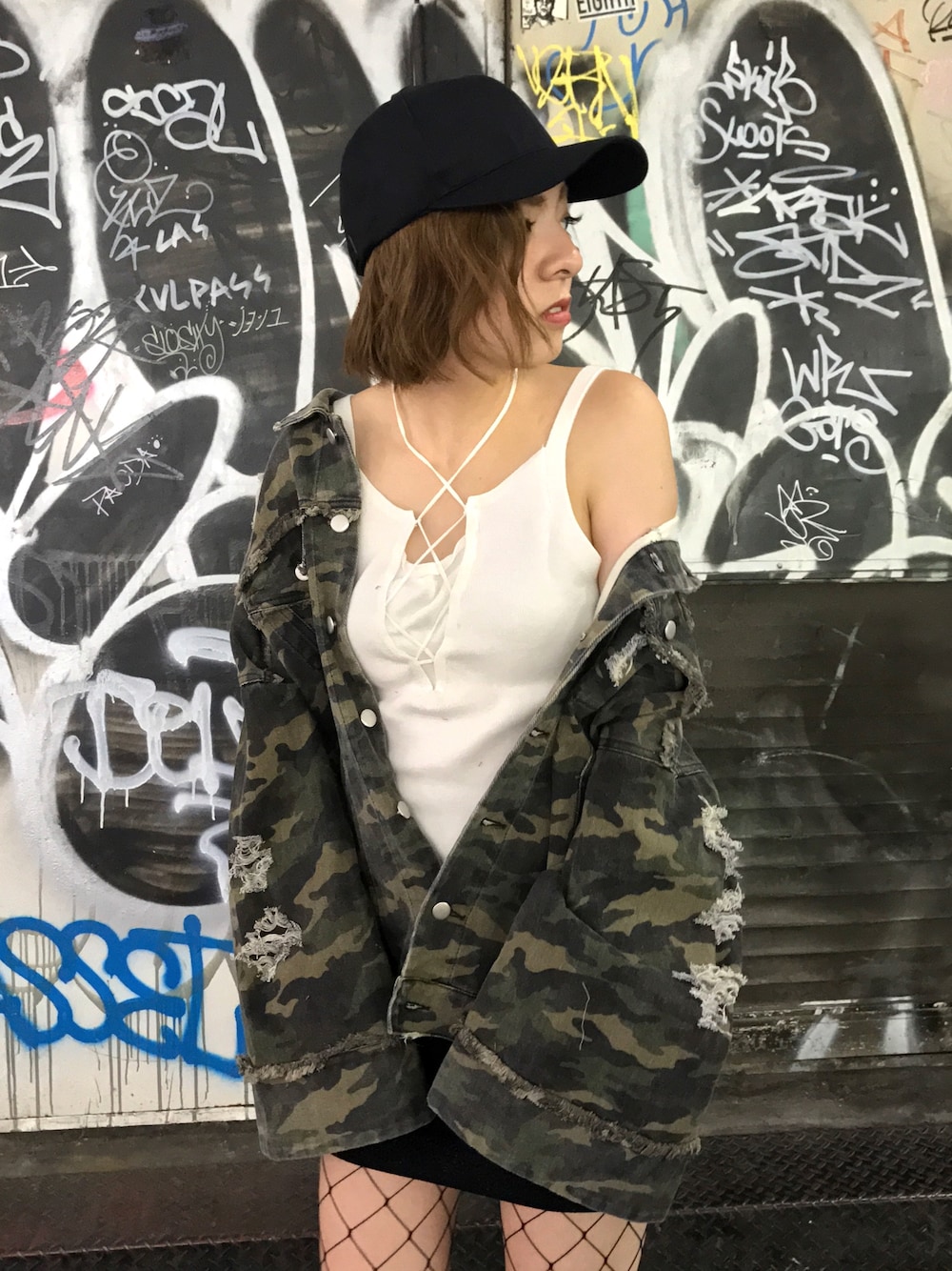 グリーン系のデニムジャケット、ホワイト系のキャミソール、ブラック系のスカートを着用したレディースの秋コーディネートの1枚目の写真