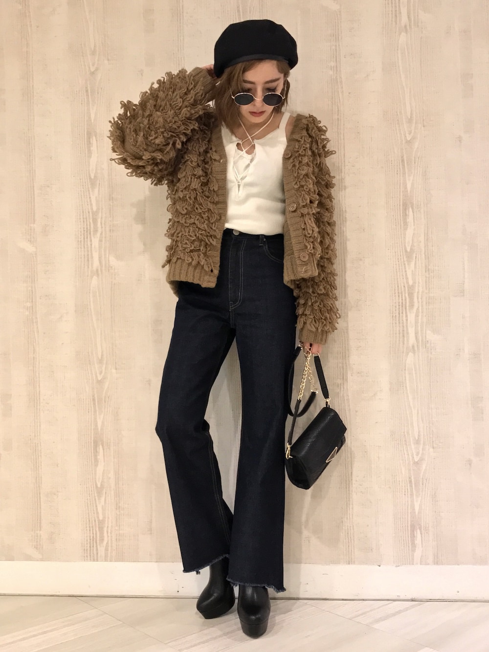 ブラウン系のカーディガン/ボレロ、ホワイト系のキャミソール、ブルー系のデニムパンツを着用したレディースの秋コーディネートの1枚目の写真