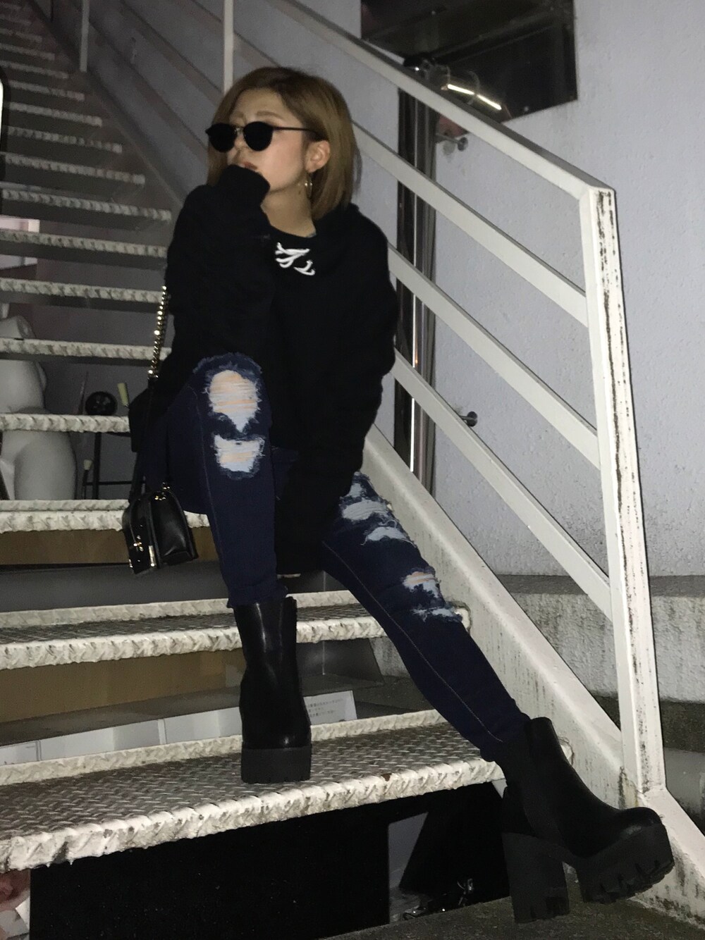 ブラック系のパーカー、ブルー系のデニムパンツ、ブラック系のブーツを着用したレディースの冬コーディネートの1枚目の写真