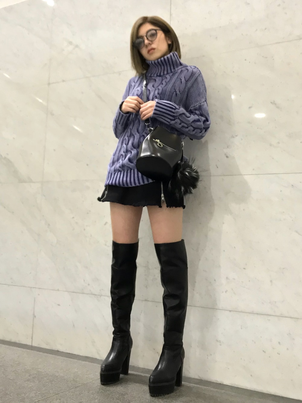 ブルー系のニット/セーター、ブラック系のデニムスカート、ブラック系のブーツを着用したレディースの冬コーディネートの1枚目の写真