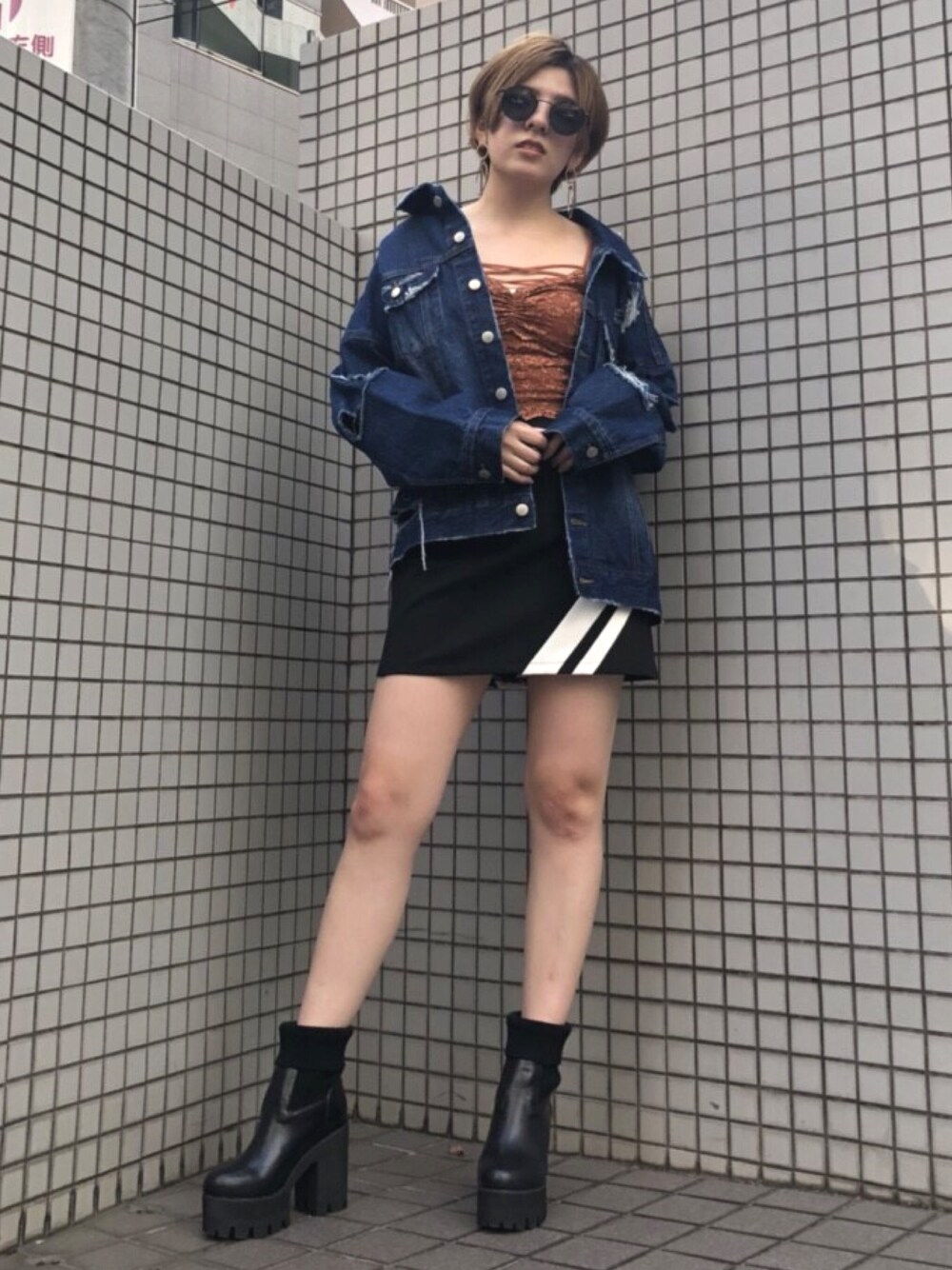 ブルー系のデニムジャケット、ブラック系のスカート、ブラウン系のキャミソールを着用したレディースの秋コーディネートの1枚目の写真