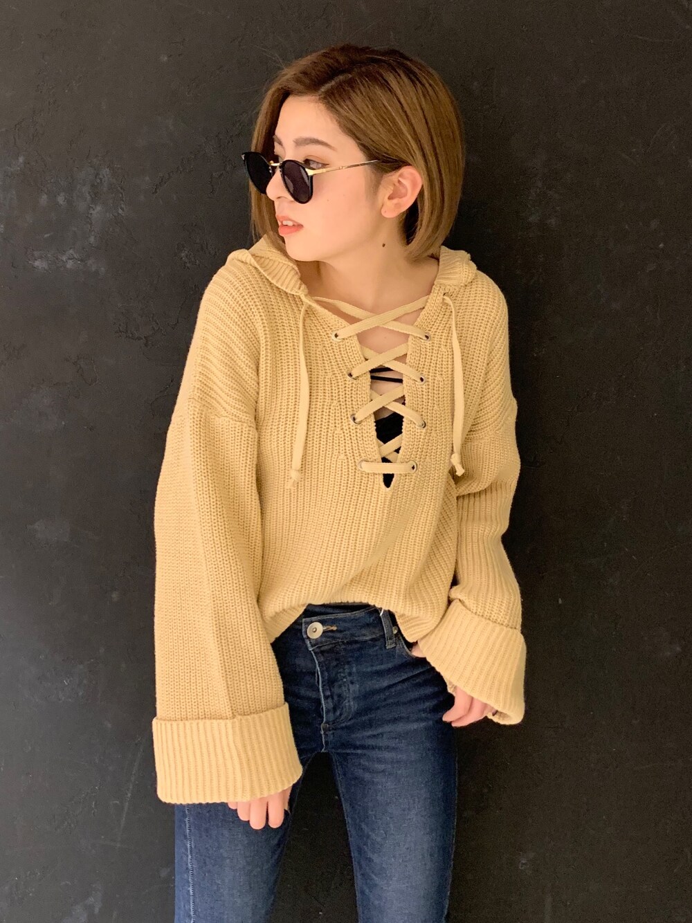 ベージュ系のニット/セーター、ブルー系のデニムパンツ、ブラック系のキャミソールを着用したレディースの冬コーディネートの1枚目の写真