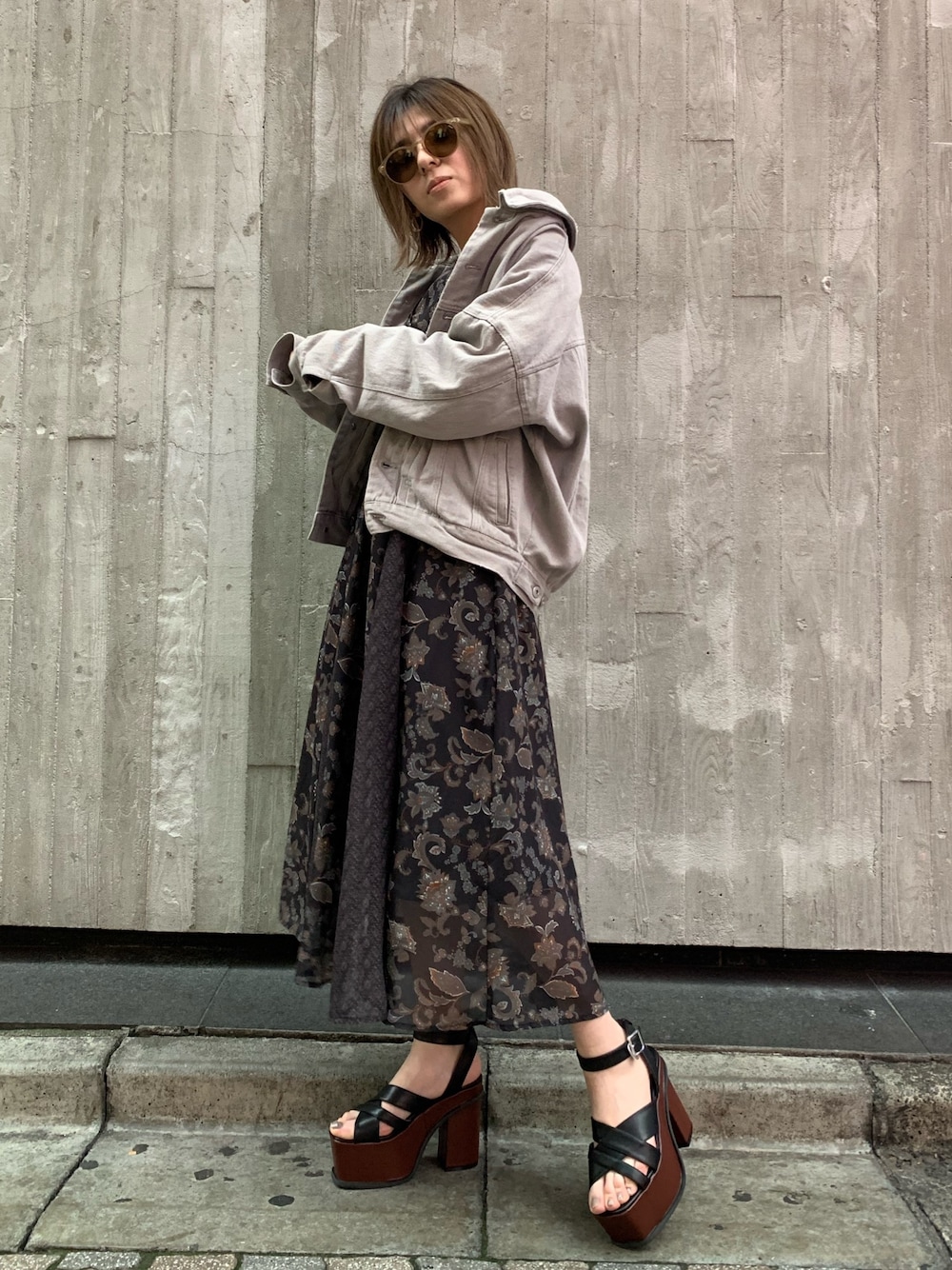 ブラック系のワンピース、グレー系のデニムジャケット、ブラウン系のサンダルを着用したレディースの冬コーディネートの1枚目の写真