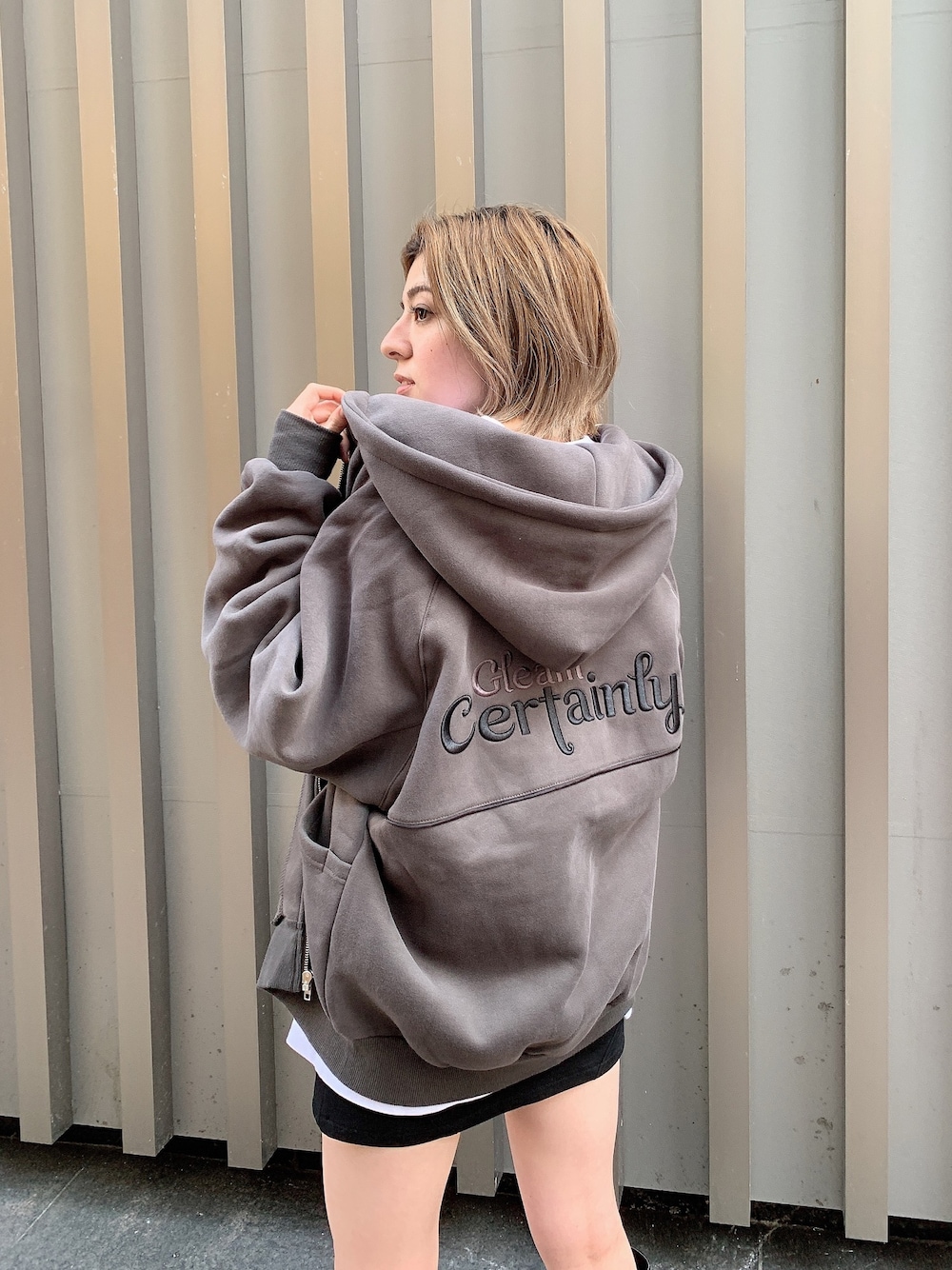 ブラック系のパーカー、ブラック系のスカートを着用したレディースの秋コーディネートの1枚目の写真