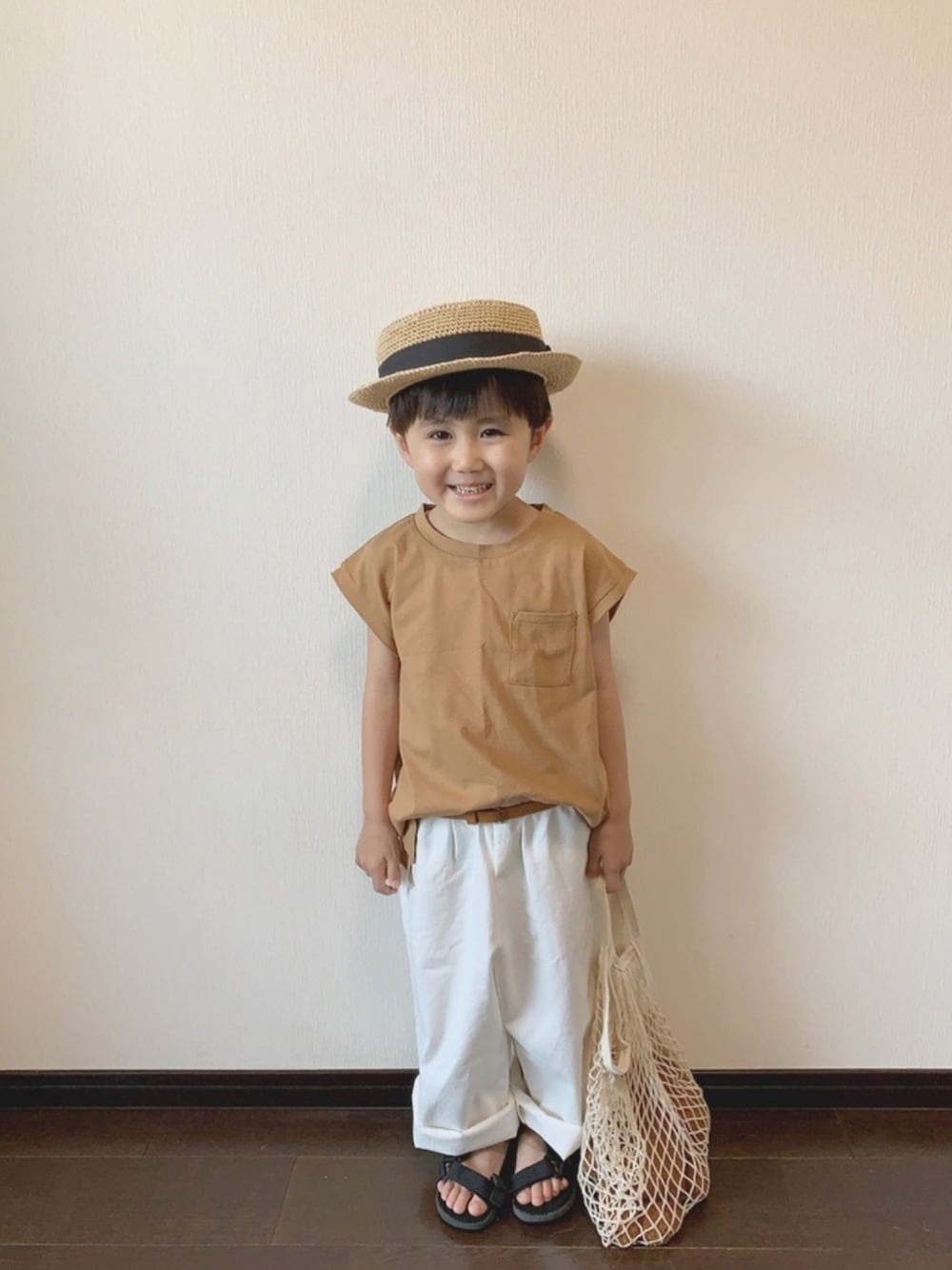 ベージュ系のTシャツ/カットソー、ホワイト系のパンツ、ブラック系のサンダルを着用したキッズの夏コーディネートの1枚目の写真