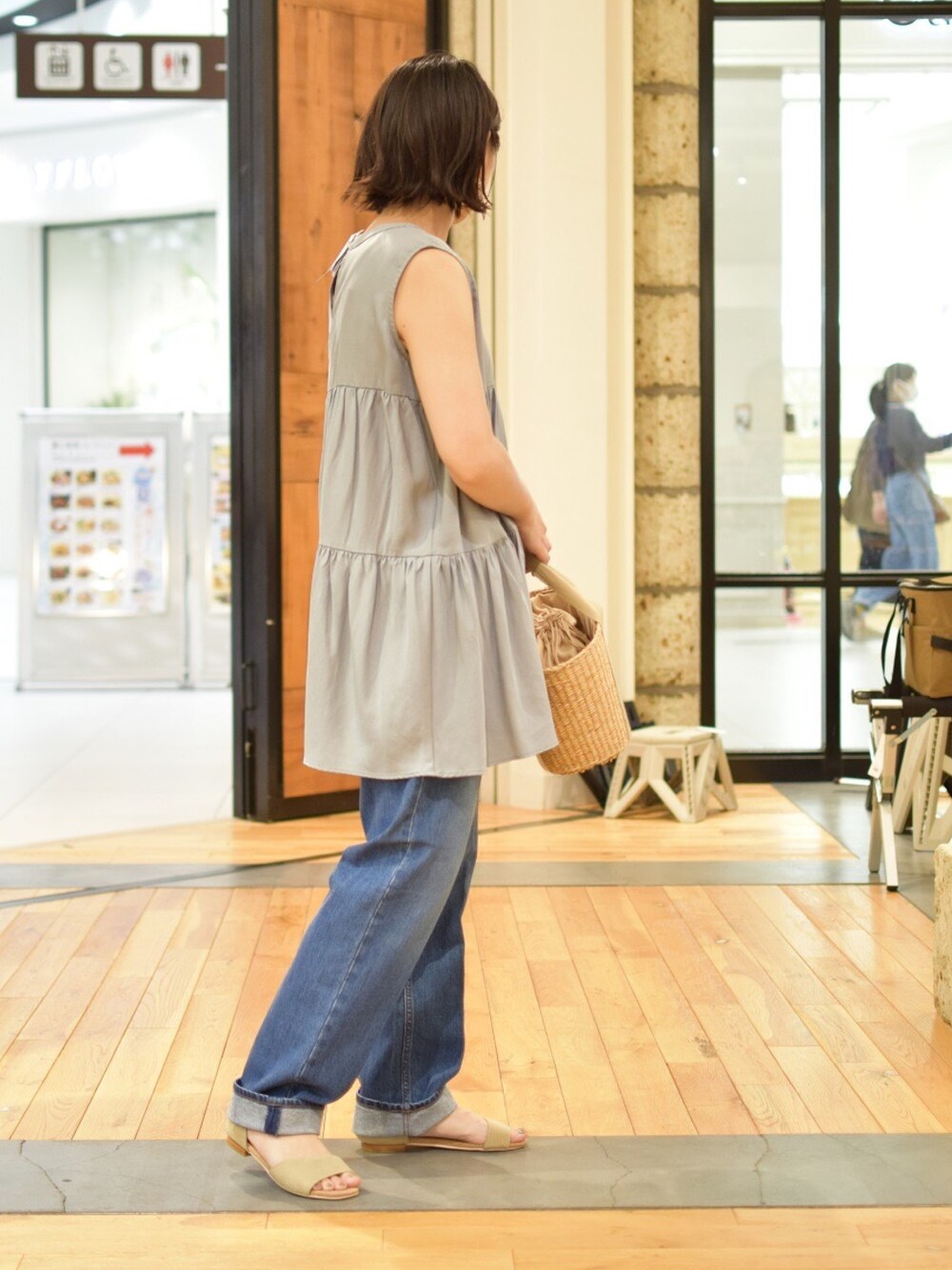 ブルー系のチュニック、ブルー系のデニムパンツ、ベージュ系のサンダルを着用したレディースの夏コーディネートの1枚目の写真