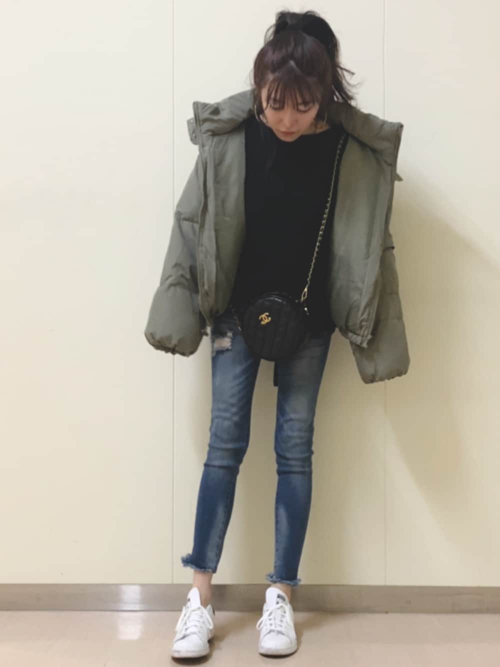 ブラック系のニット/セーター、グリーン系のダウンジャケット/コート、ブルー系のデニムパンツを着用したレディースの秋コーディネートの1枚目の写真