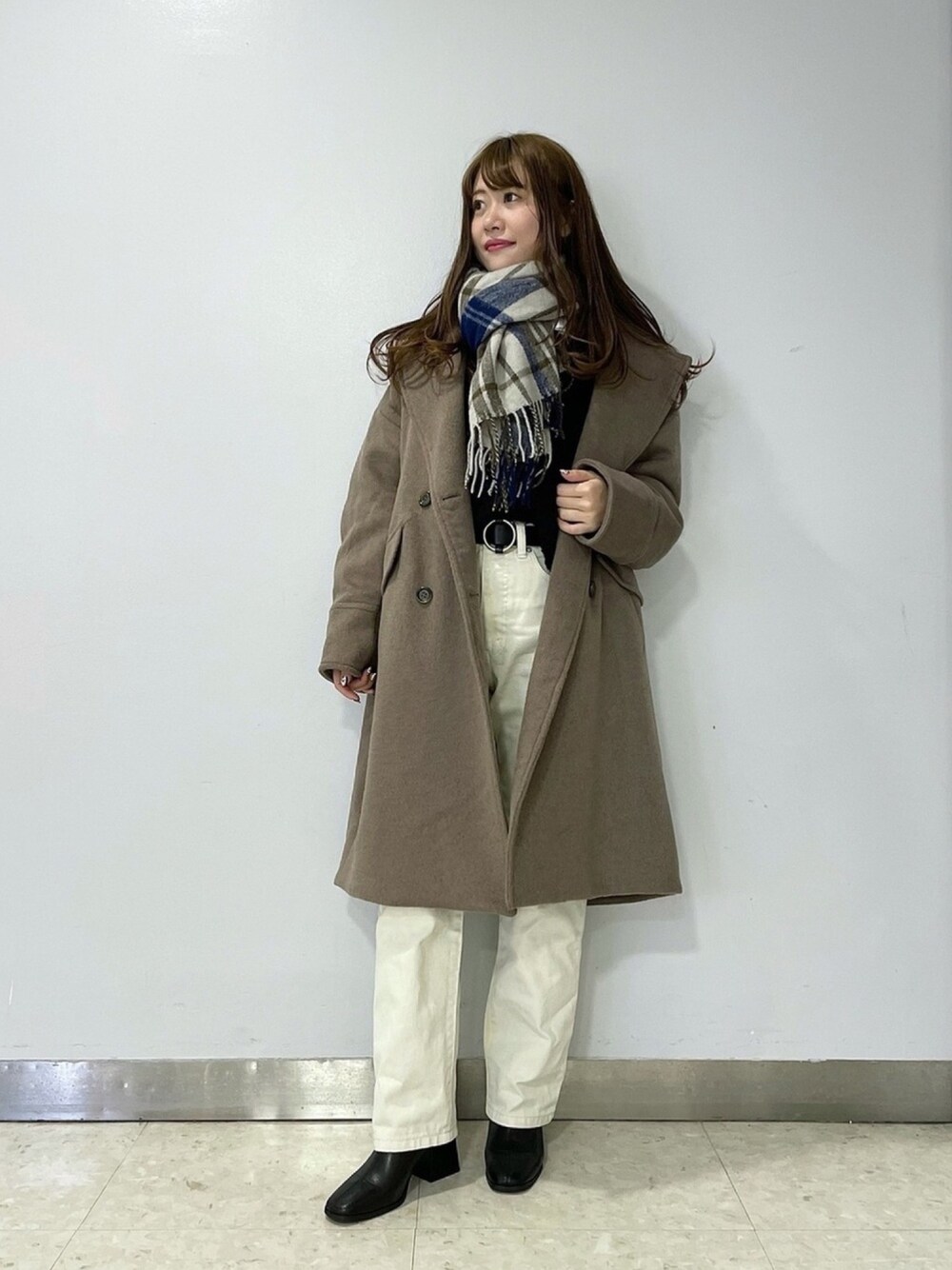 ブラック系のニット/セーター、ホワイト系のデニムパンツ、ブラウン系のチェスターコートを着用したレディースの冬コーディネートの1枚目の写真