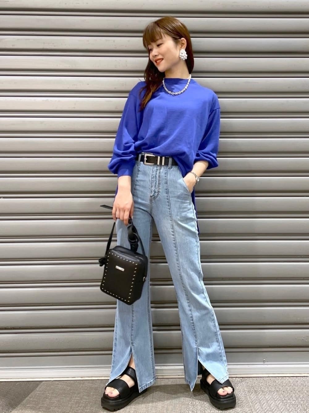 ブルー系のニット/セーター、ブルー系のデニムパンツ、ブラック系のショルダーバッグを着用したレディースの春コーディネートの1枚目の写真