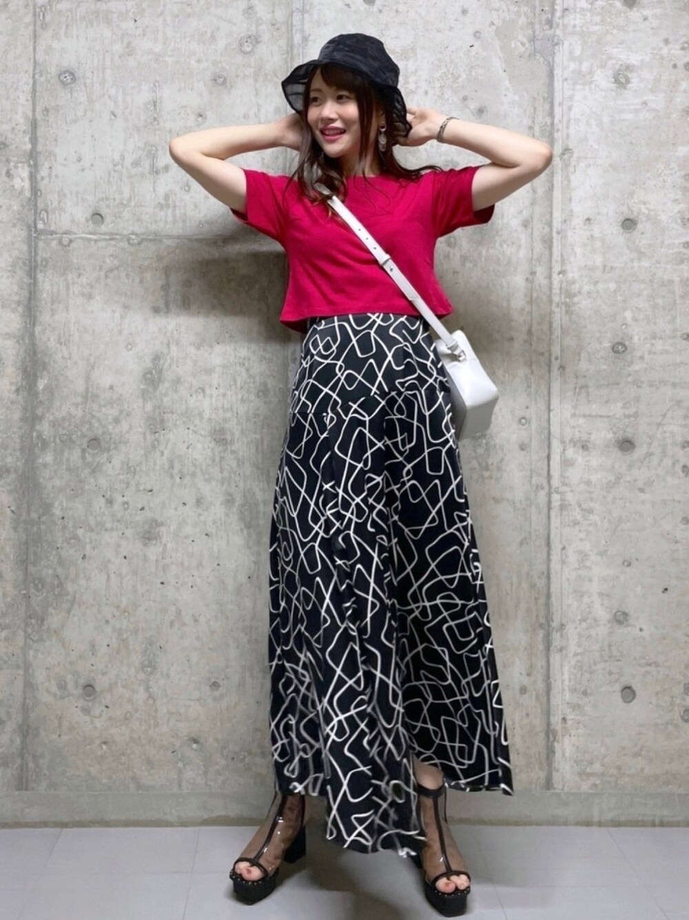 ホワイト系のショルダーバッグ、ブラック系のスカート、レッド系のTシャツ/カットソーを着用したレディースの春コーディネートの1枚目の写真