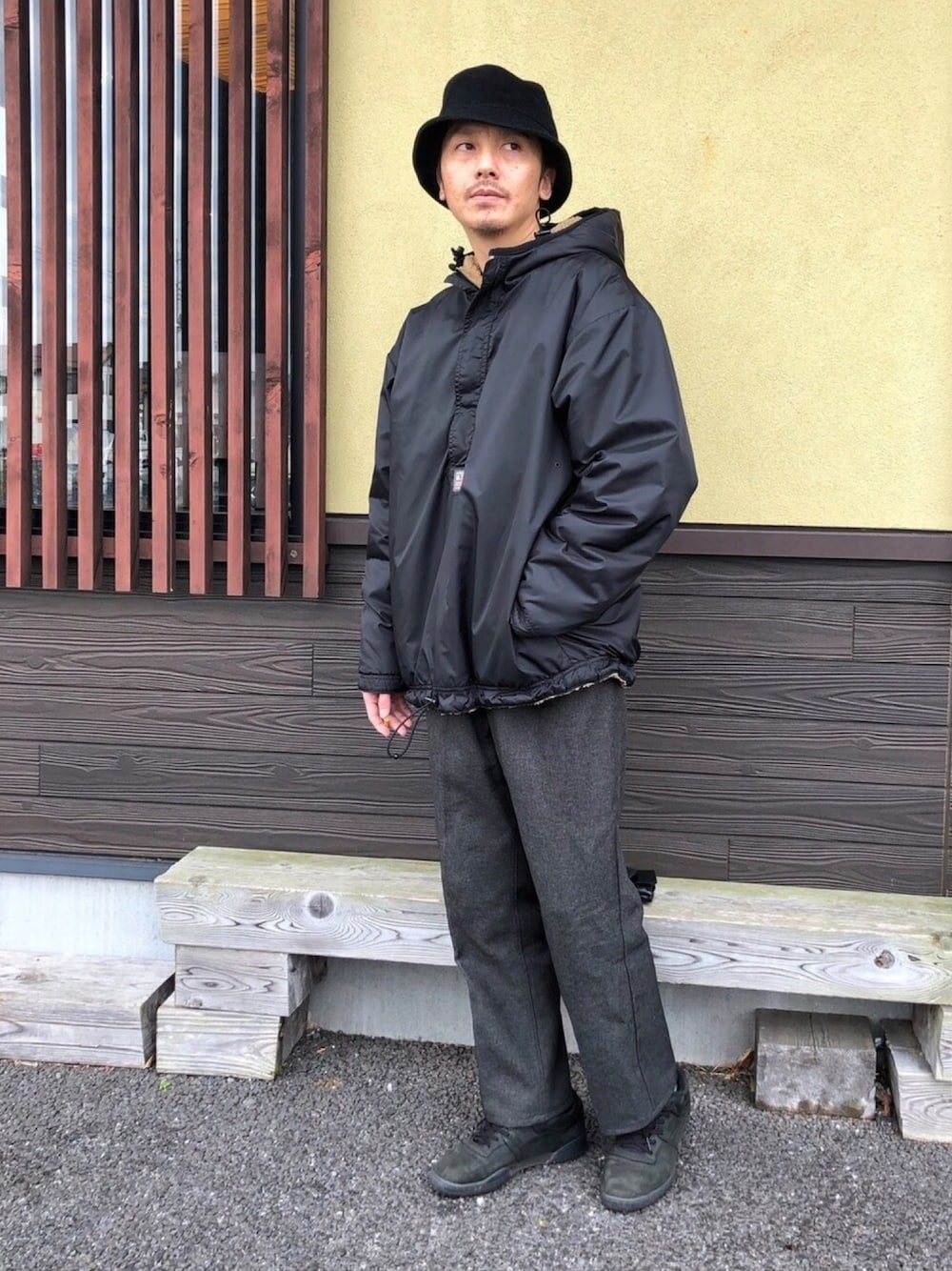 グレー系のスラックス、ブラック系のスニーカー、ブラック系のパーカーを着用したメンズの冬コーディネートの1枚目の写真