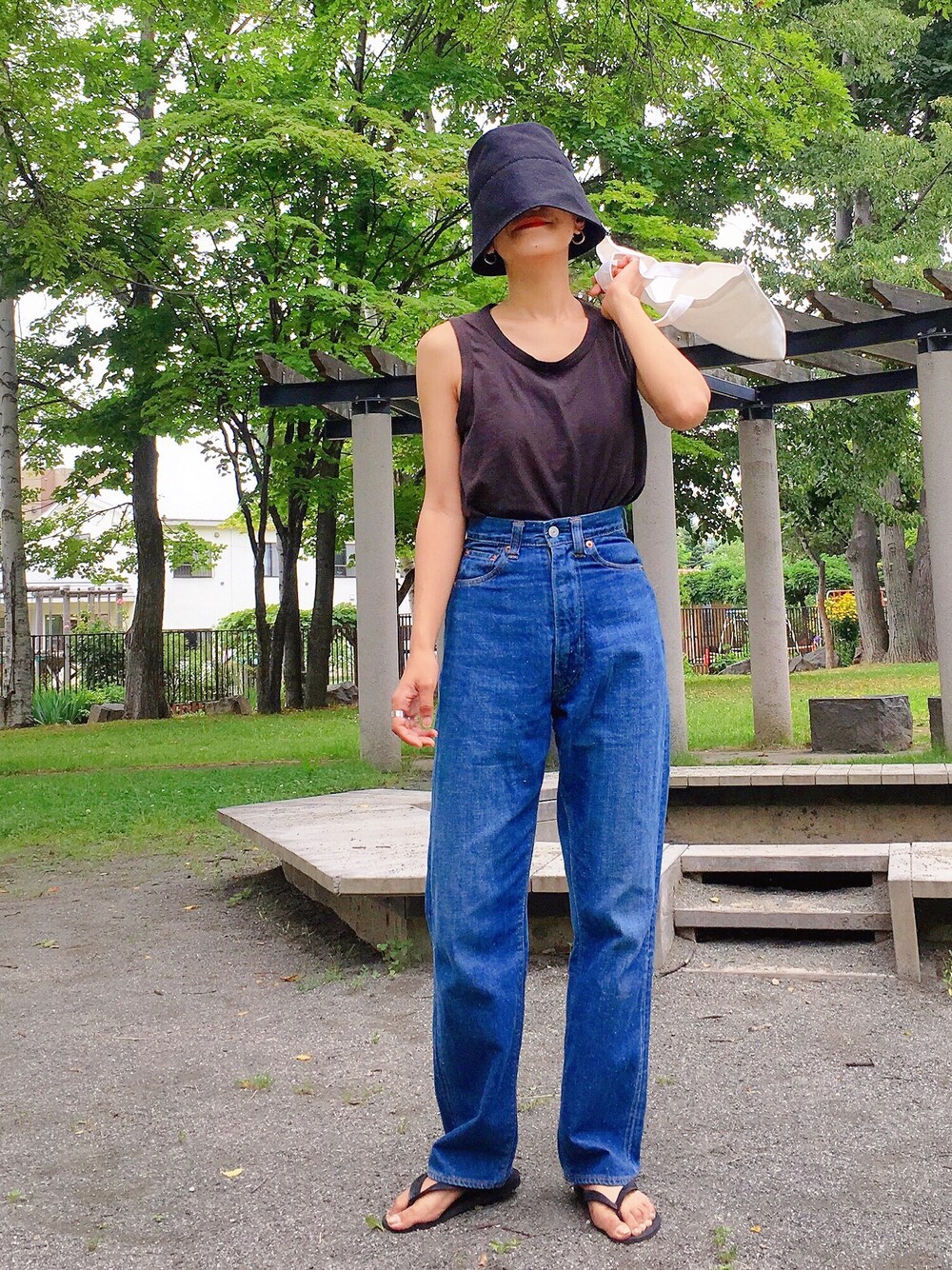 ブラック系のタンクトップ、ブルー系のデニムパンツ、ブラック系のサンダルを着用したレディースの夏コーディネートの1枚目の写真