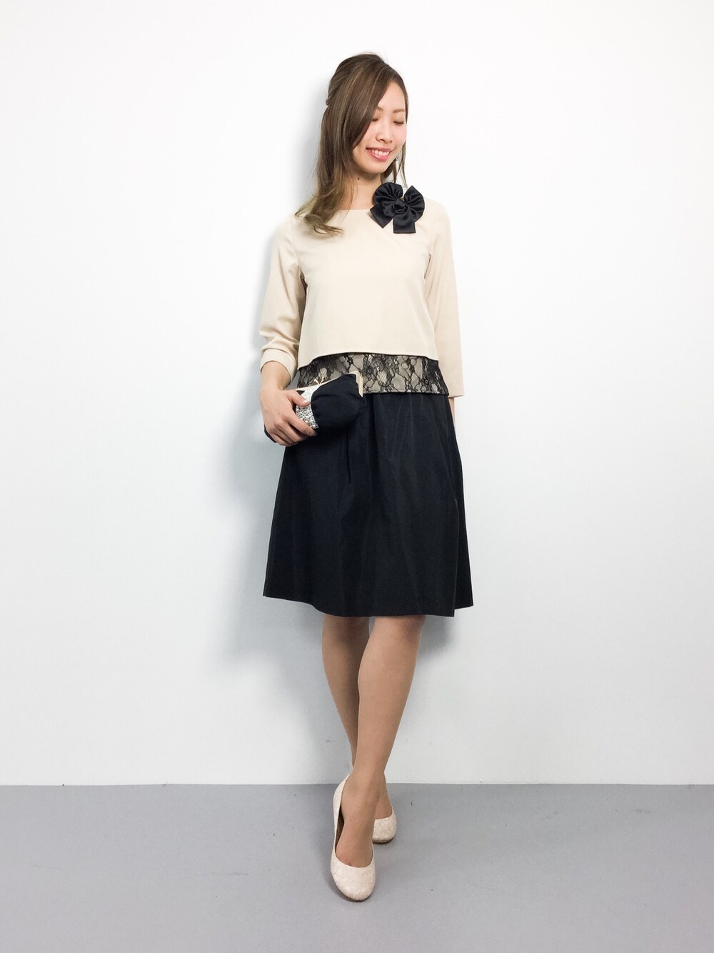 ベージュ系のドレス、ブラック系のクラッチバッグを着用したレディースの冬コーディネートの1枚目の写真