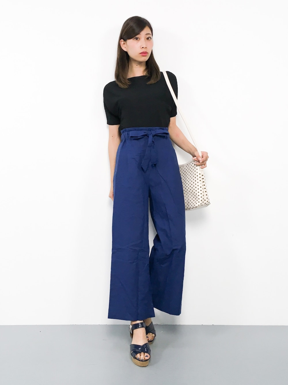 ブラック系のニット/セーター、ブルー系のその他パンツ、ホワイト系のショルダーバッグを着用したレディースの夏コーディネートの1枚目の写真