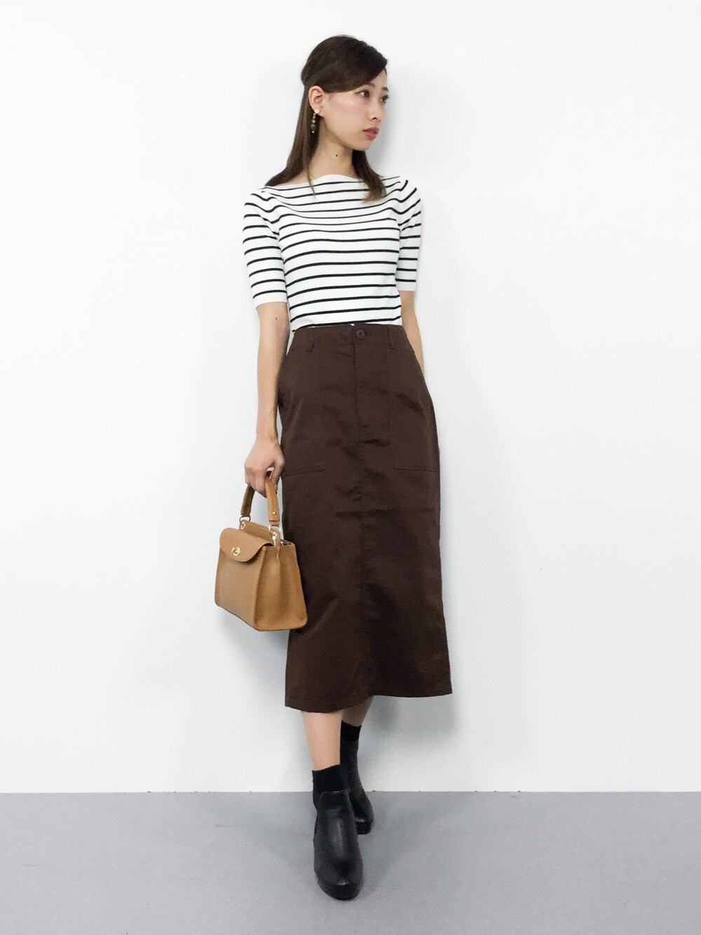 ホワイト系のニット/セーター、ブラウン系のスカート、ブラウン系のショルダーバッグを着用したレディースの秋コーディネートの1枚目の写真