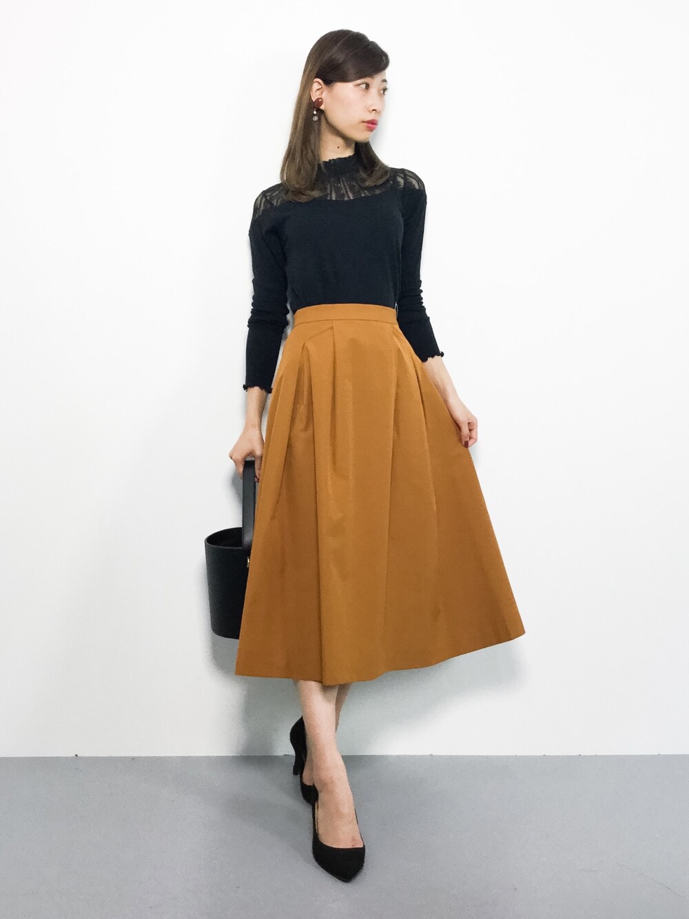 ブラック系のTシャツ/カットソー、イエロー系のスカートを着用したレディースの秋コーディネートの1枚目の写真