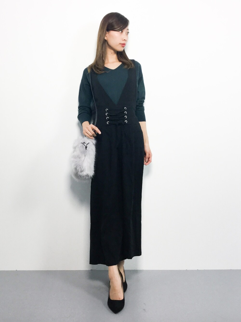 グリーン系のニット/セーター、ブラック系のつなぎ/オールインワン、グレー系のショルダーバッグを着用したレディースの秋コーディネートの1枚目の写真