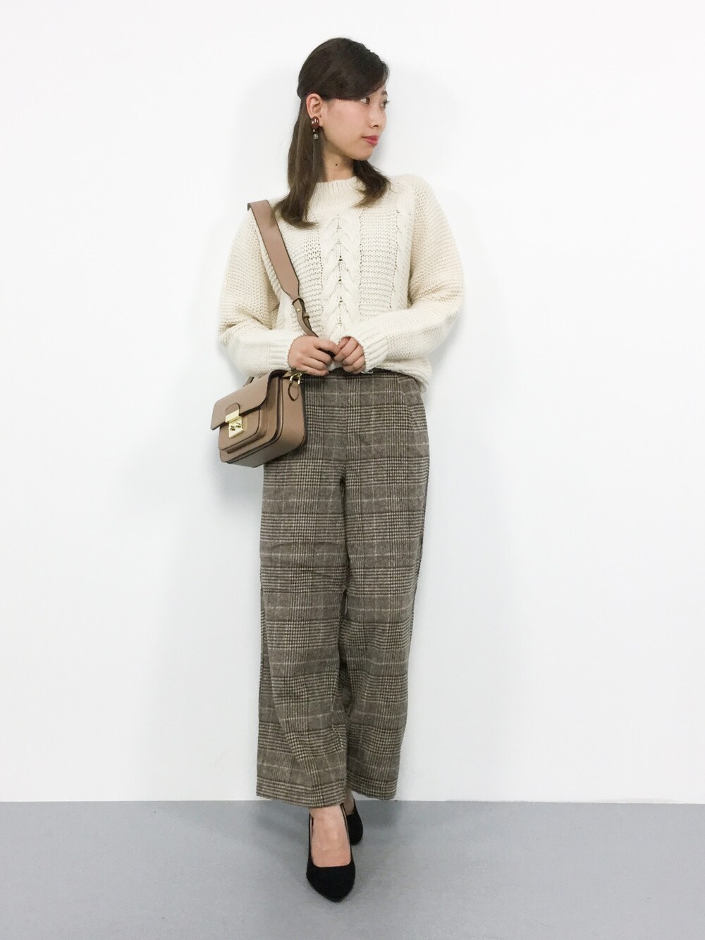 ベージュ系のニット/セーター、ブラウン系のその他パンツ、ベージュ系のショルダーバッグを着用したレディースの冬コーディネートの1枚目の写真