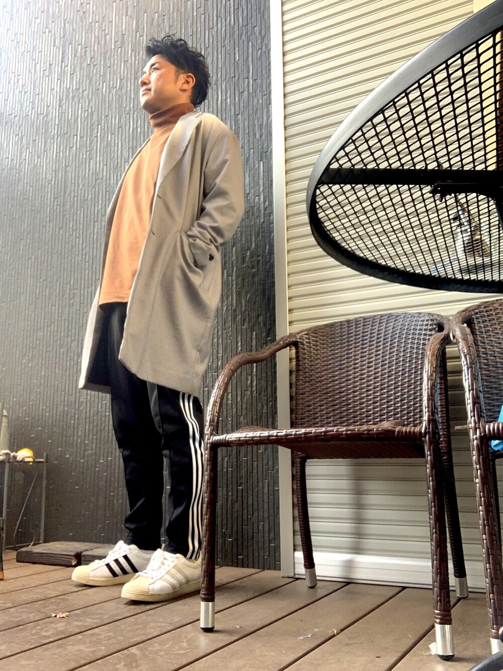 グレー系のチェスターコート、ブラック系のその他パンツ、ホワイト系のスニーカーを着用したメンズの冬コーディネートの1枚目の写真