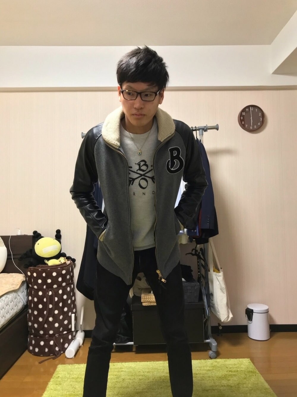 グレー系のスタジャン、ホワイト系のニット/セーター、ブラック系のデニムパンツを着用したメンズの冬コーディネートの1枚目の写真