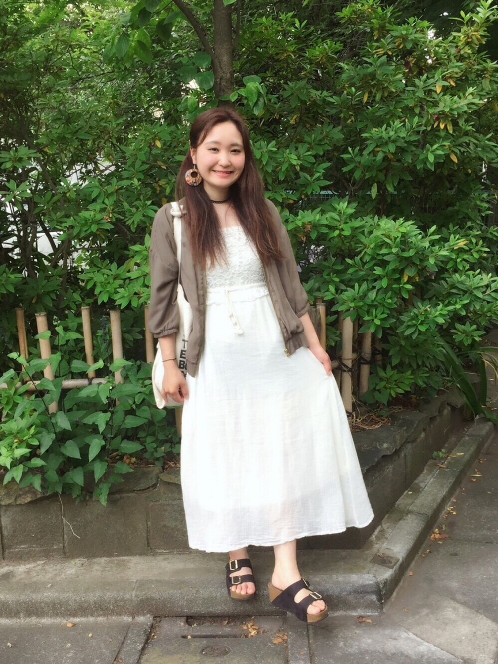 グリーン系のブルゾン、ホワイト系のワンピース、ブラック系のサンダルを着用したレディースの夏コーディネートの1枚目の写真