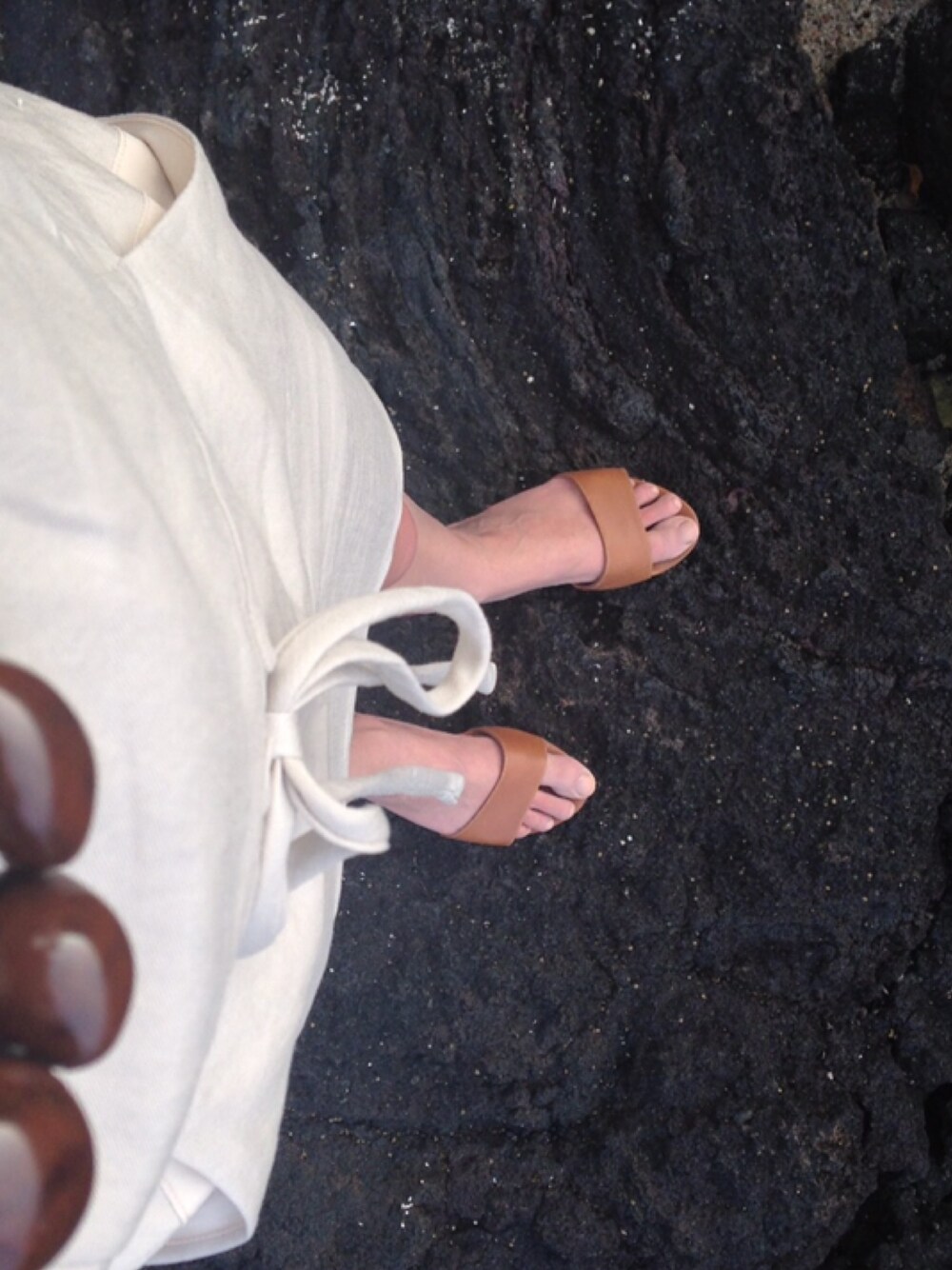 ブラウン系のサンダル、ベージュ系のワンピースを着用したレディースの春コーディネートの1枚目の写真