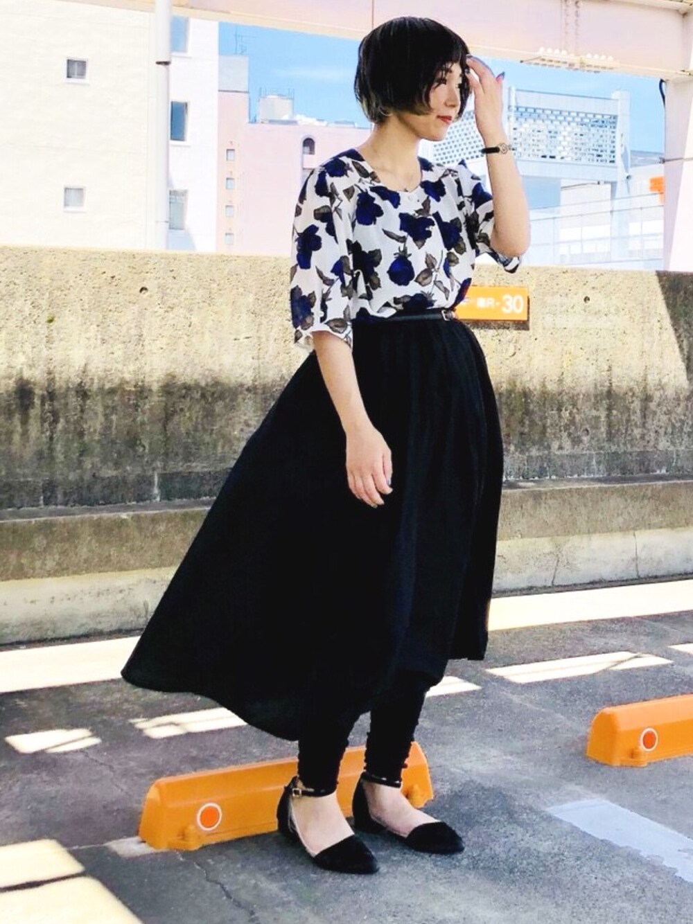 ホワイト系のトップス、ブラック系のスカート、ブラック系のレッグウォーマーを着用したレディースの夏コーディネートの1枚目の写真