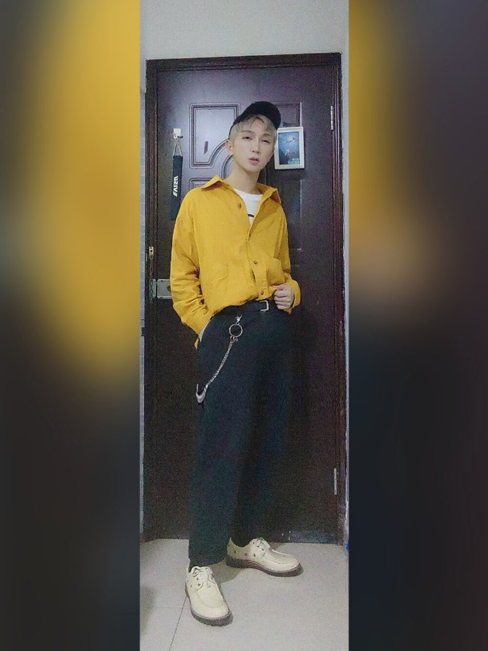 ブラック系のスラックス、イエロー系のニット/セーター、ホワイト系のTシャツ/カットソーを着用したメンズの秋コーディネートの1枚目の写真