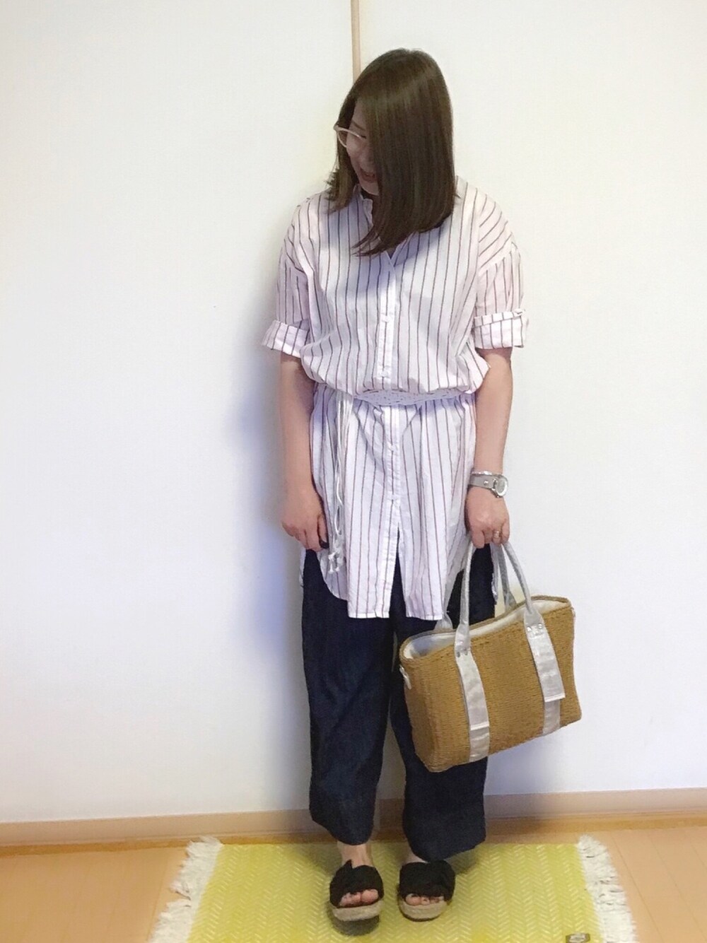 ホワイト系のシャツワンピース、シルバー系のかごバッグ、ブルー系のデニムパンツを着用したレディースの春コーディネートの1枚目の写真