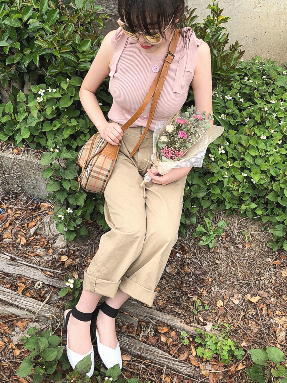 ピンク系のニット/セーター、ベージュ系のチノパンツ、ブラウン系のショルダーバッグを着用したレディースの春コーディネートの1枚目の写真