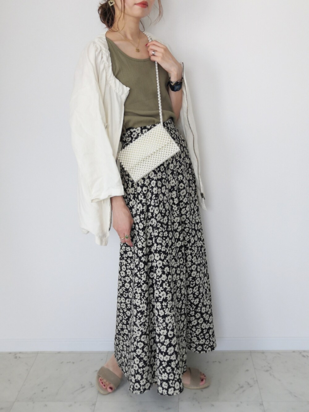 グリーン系のタンクトップ、ブラック系のスカート、ホワイト系のバッグを着用したレディースの夏コーディネートの1枚目の写真