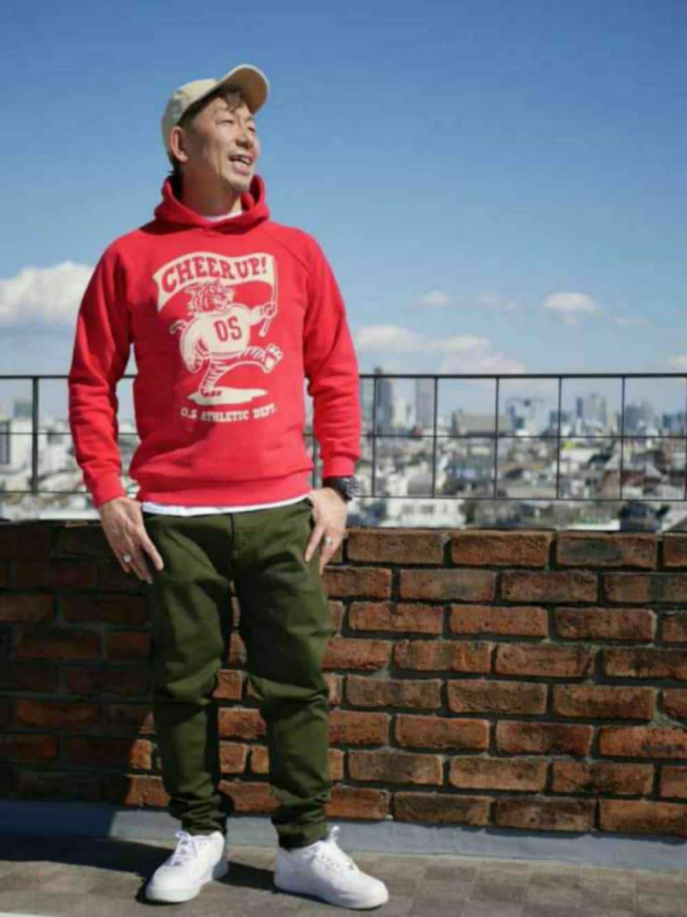 レッド系のパーカー、グリーン系のその他パンツ、ホワイト系のスニーカーを着用したメンズの秋コーディネートの1枚目の写真