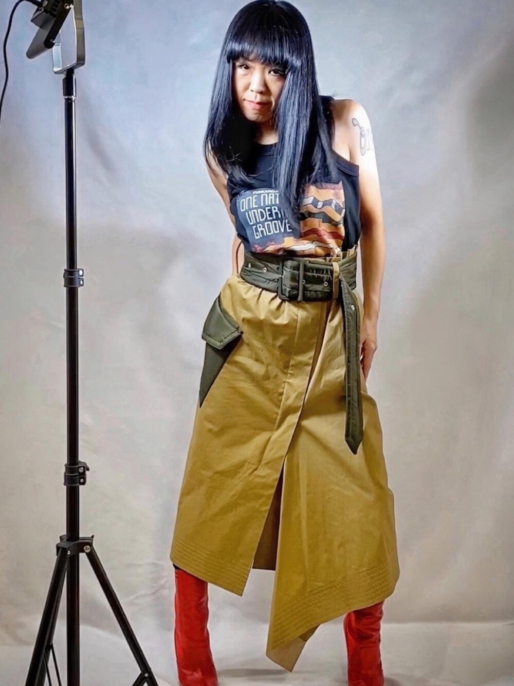 ブラック系のタンクトップ、ベージュ系のスカート、レッド系のブーツを着用したレディースの春コーディネートの1枚目の写真