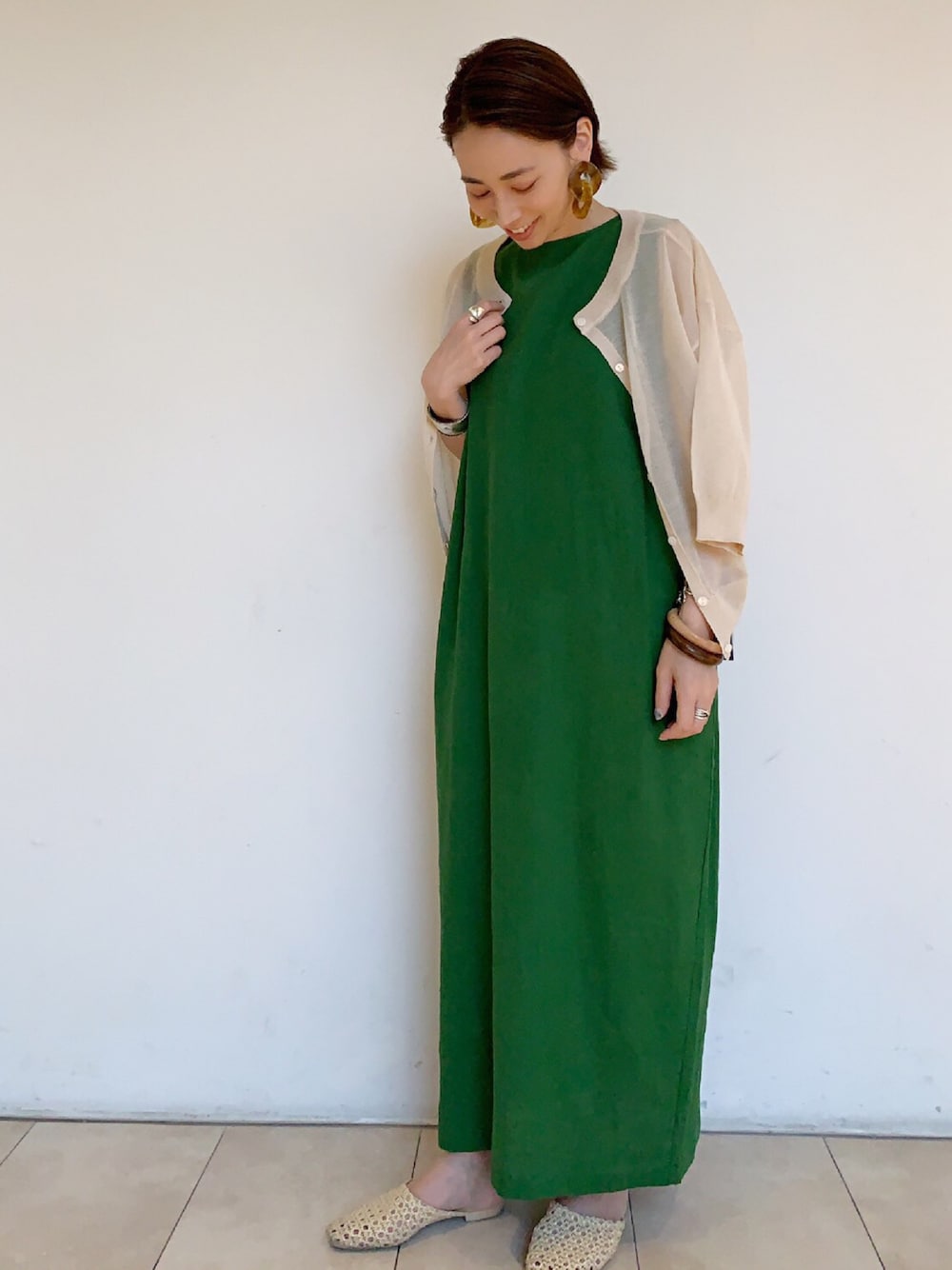 ベージュ系のサンダル、グリーン系のワンピース、ベージュ系のカーディガン/ボレロを着用したレディースの春コーディネートの1枚目の写真