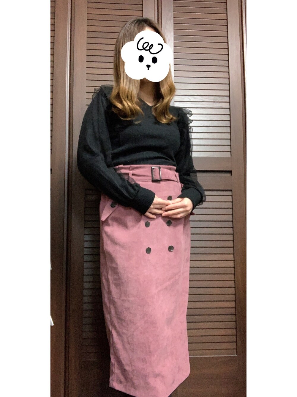 ブラック系のトップス、ピンク系のスカートを着用したレディースの冬コーディネートの1枚目の写真