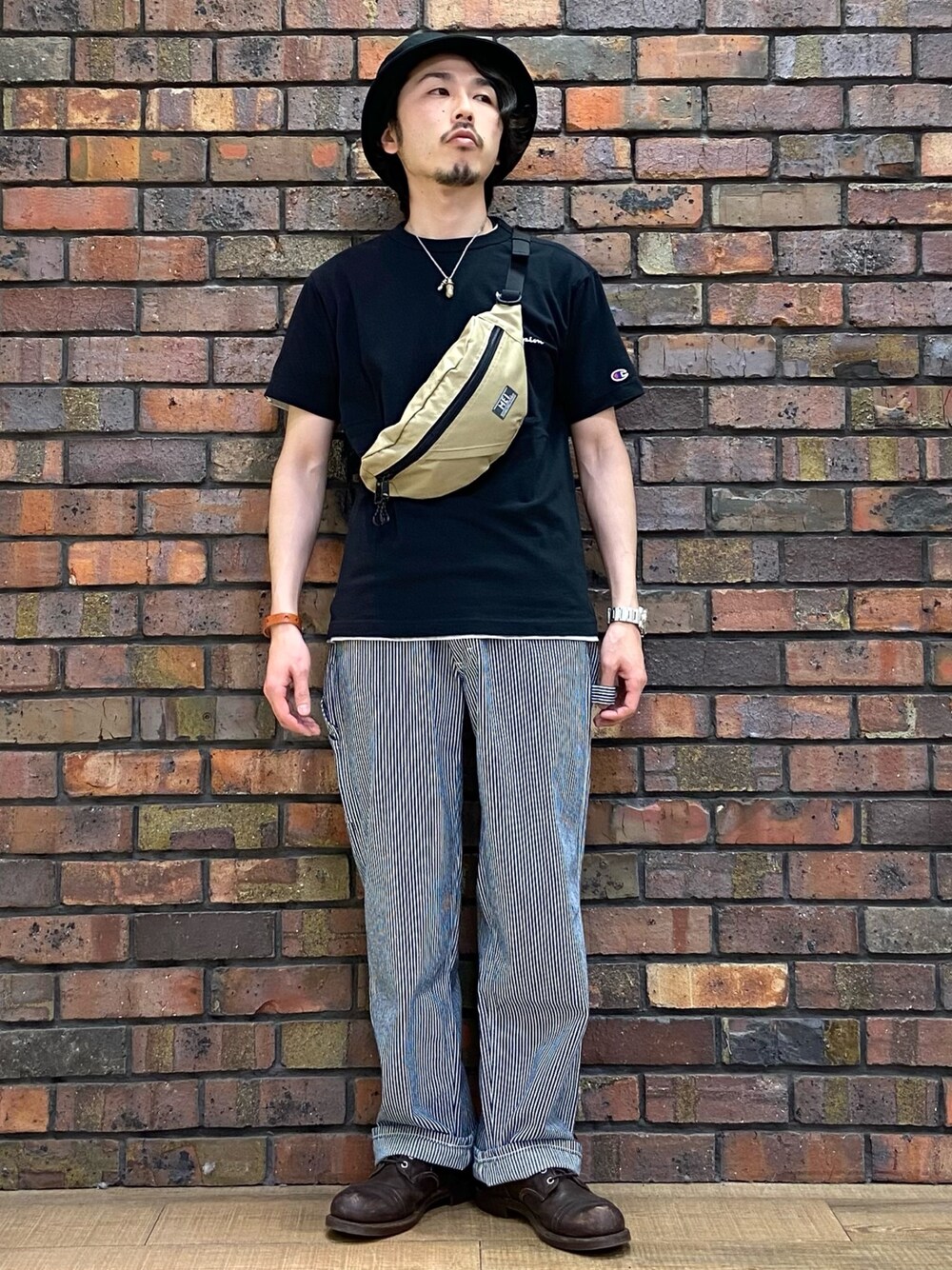 ブラック系のTシャツ/カットソー、ベージュ系のボディバッグ/ウエストポーチ、その他のデニムパンツを着用したメンズの春コーディネートの1枚目の写真