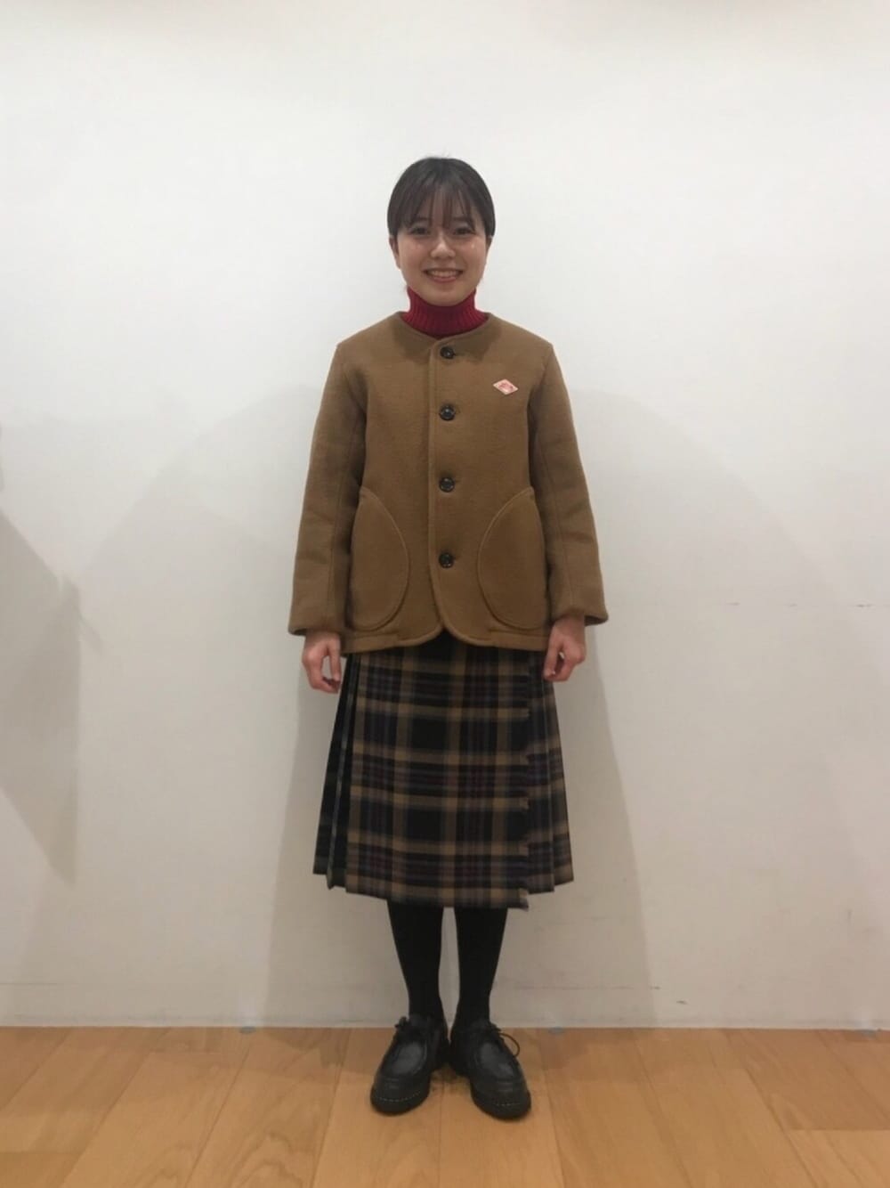 レッド系のニット/セーター、ベージュ系のスカート、ブラック系のドレスシューズを着用したレディースの秋コーディネートの1枚目の写真