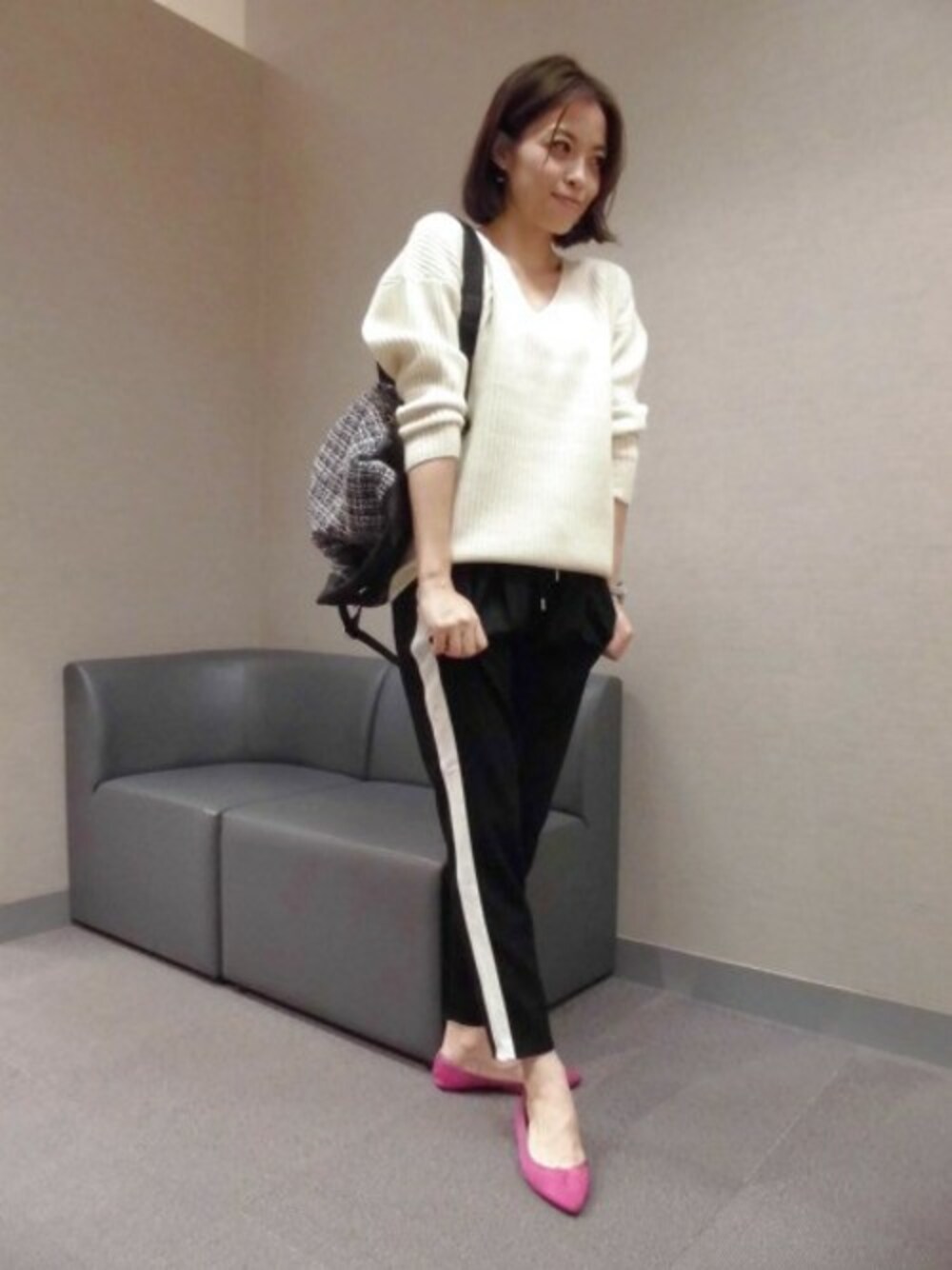 イエロー系のニット/セーター、グレー系のその他パンツ、その他のバックパック/リュックを着用したレディースの秋コーディネートの1枚目の写真