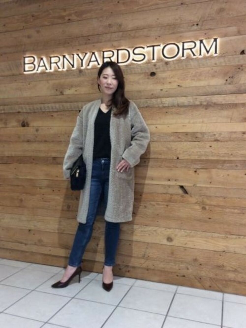 ブラウン系のムートンコート、グレー系のTシャツ/カットソー、ブルー系のデニムパンツを着用したレディースの秋コーディネートの1枚目の写真