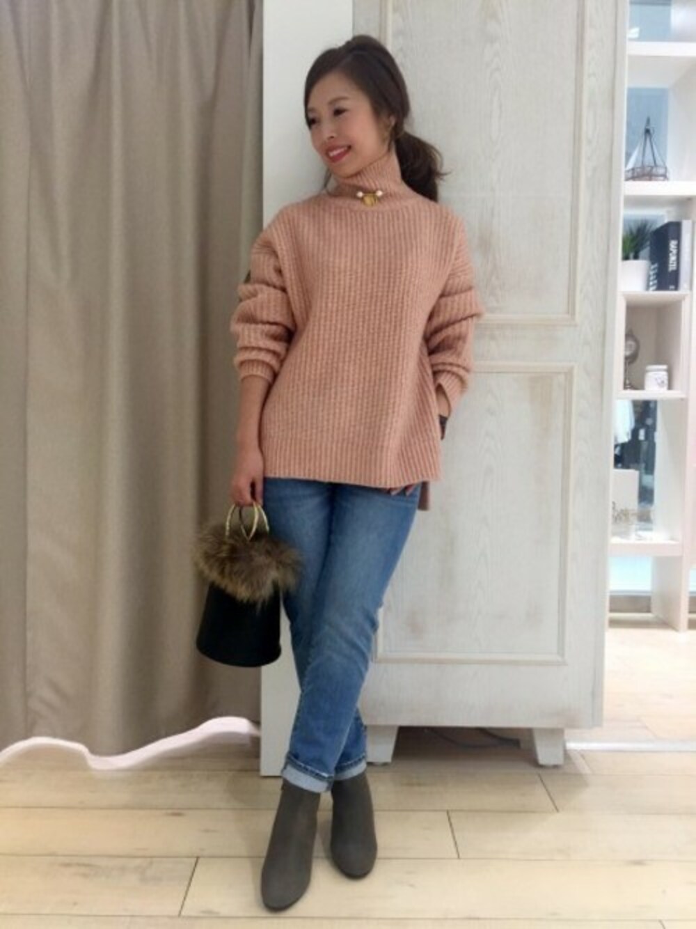 ピンク系のニット/セーター、ブルー系のデニムパンツ、グレー系のブーツを着用したレディースの秋コーディネートの1枚目の写真