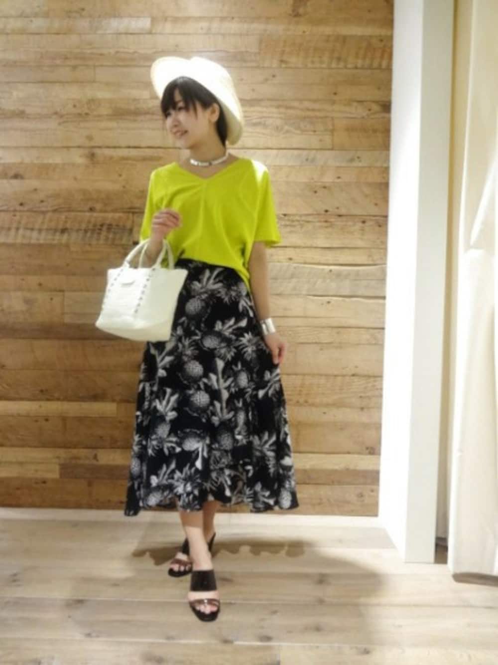 イエロー系のTシャツ/カットソー、ブラック系のスカート、ブラック系のサンダルを着用したレディースの春コーディネートの1枚目の写真