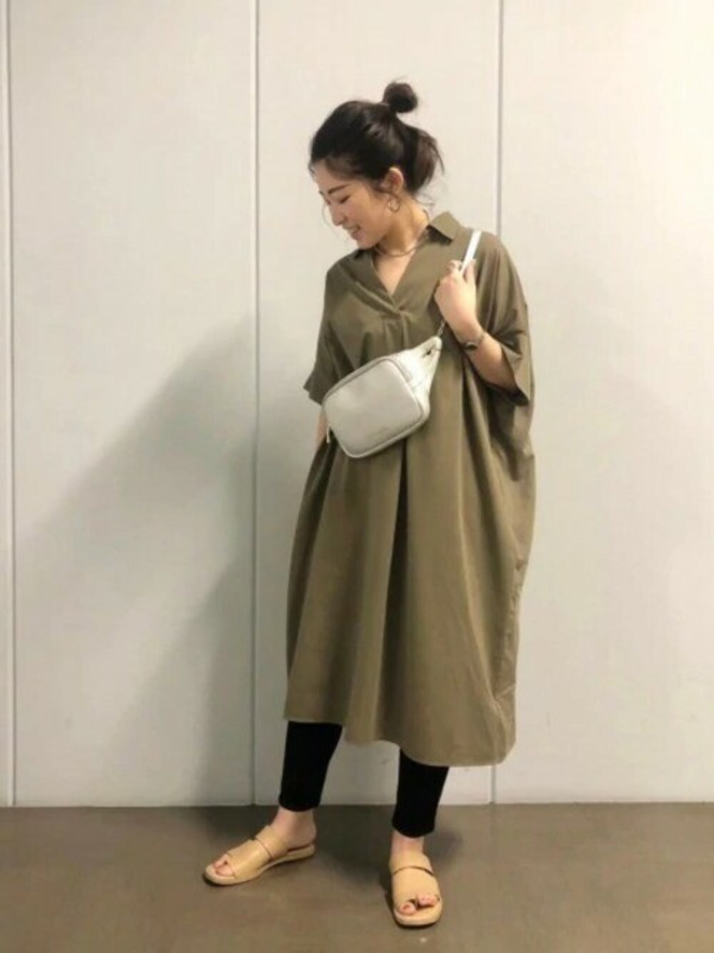 グリーン系のワンピース、ブラック系のデニムパンツ、シルバー系のボディバッグ/ウエストポーチを着用したレディースの夏コーディネートの1枚目の写真