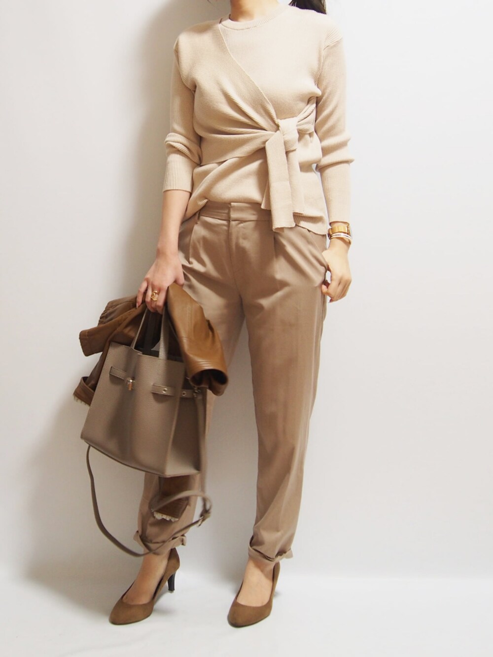 ブラウン系のパンプス、ベージュ系のニット/セーターを着用したレディースの春コーディネートの1枚目の写真