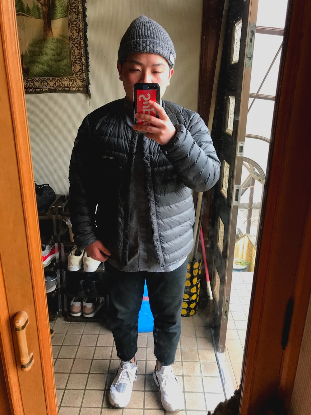 グレー系のダウンジャケット/コート、グレー系のシャツ/ブラウス、ホワイト系のスニーカーを着用したメンズの秋コーディネートの1枚目の写真