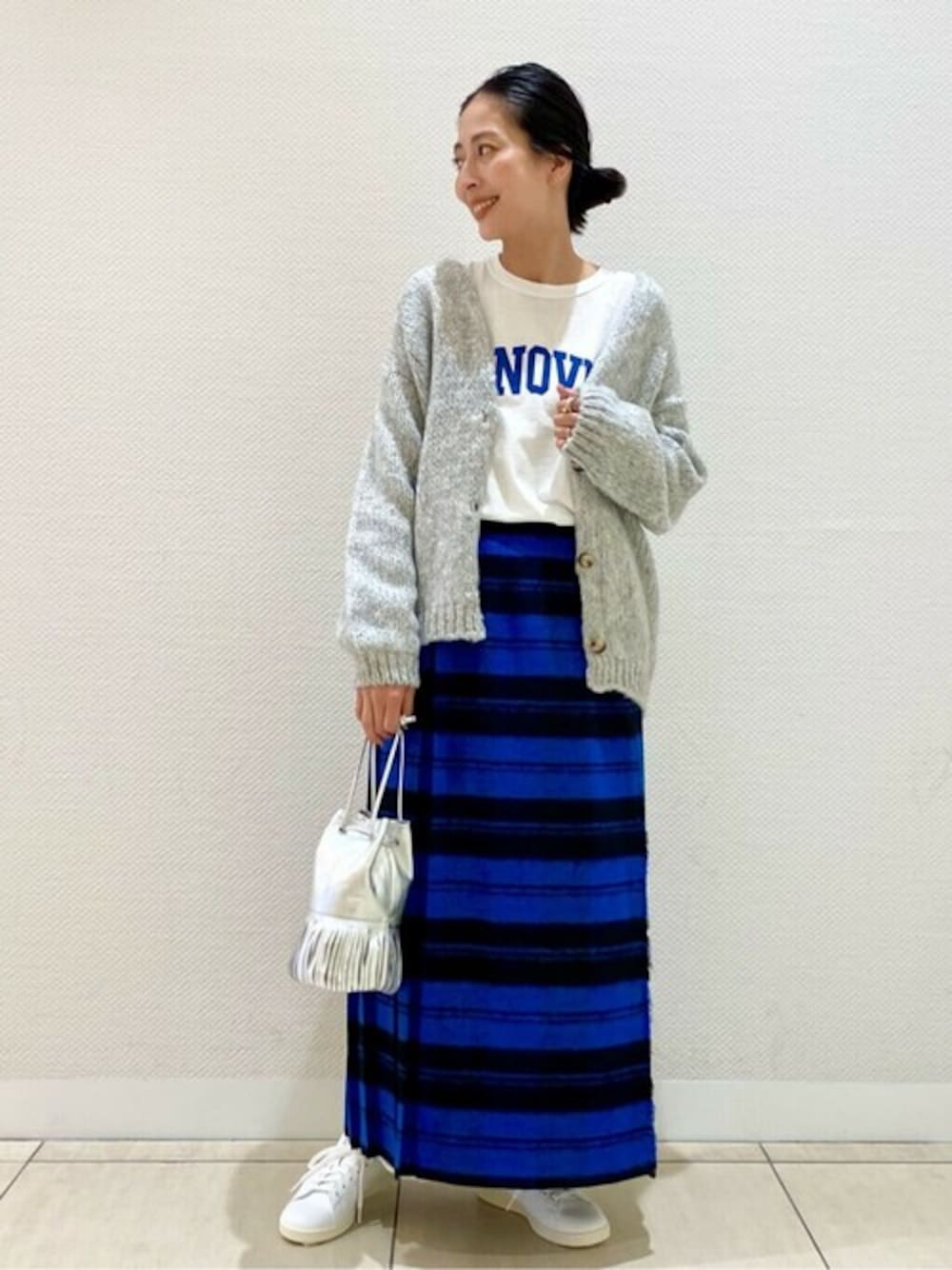 ホワイト系のTシャツ/カットソー、グレー系のカーディガン/ボレロ、ブルー系のスカートを着用したレディースの秋コーディネートの1枚目の写真
