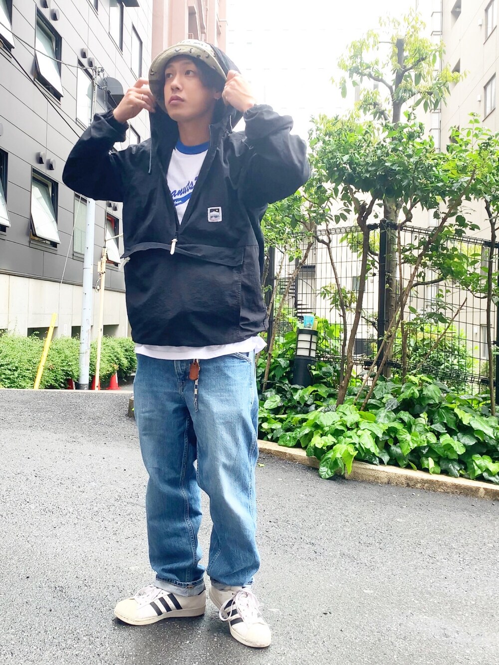 ブラック系のマウンテンパーカー、ブルー系のデニムパンツ、ホワイト系のスニーカーを着用したメンズの春コーディネートの1枚目の写真