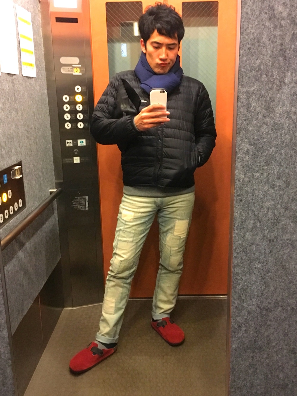 ブラック系のダウンジャケット/コート、ブルー系のデニムパンツ、レッド系のサンダルを着用したメンズの冬コーディネートの1枚目の写真