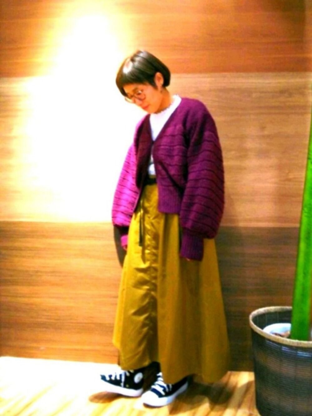 イエロー系のスカート、パープル系のカーディガン/ボレロを着用したレディースの秋コーディネートの1枚目の写真