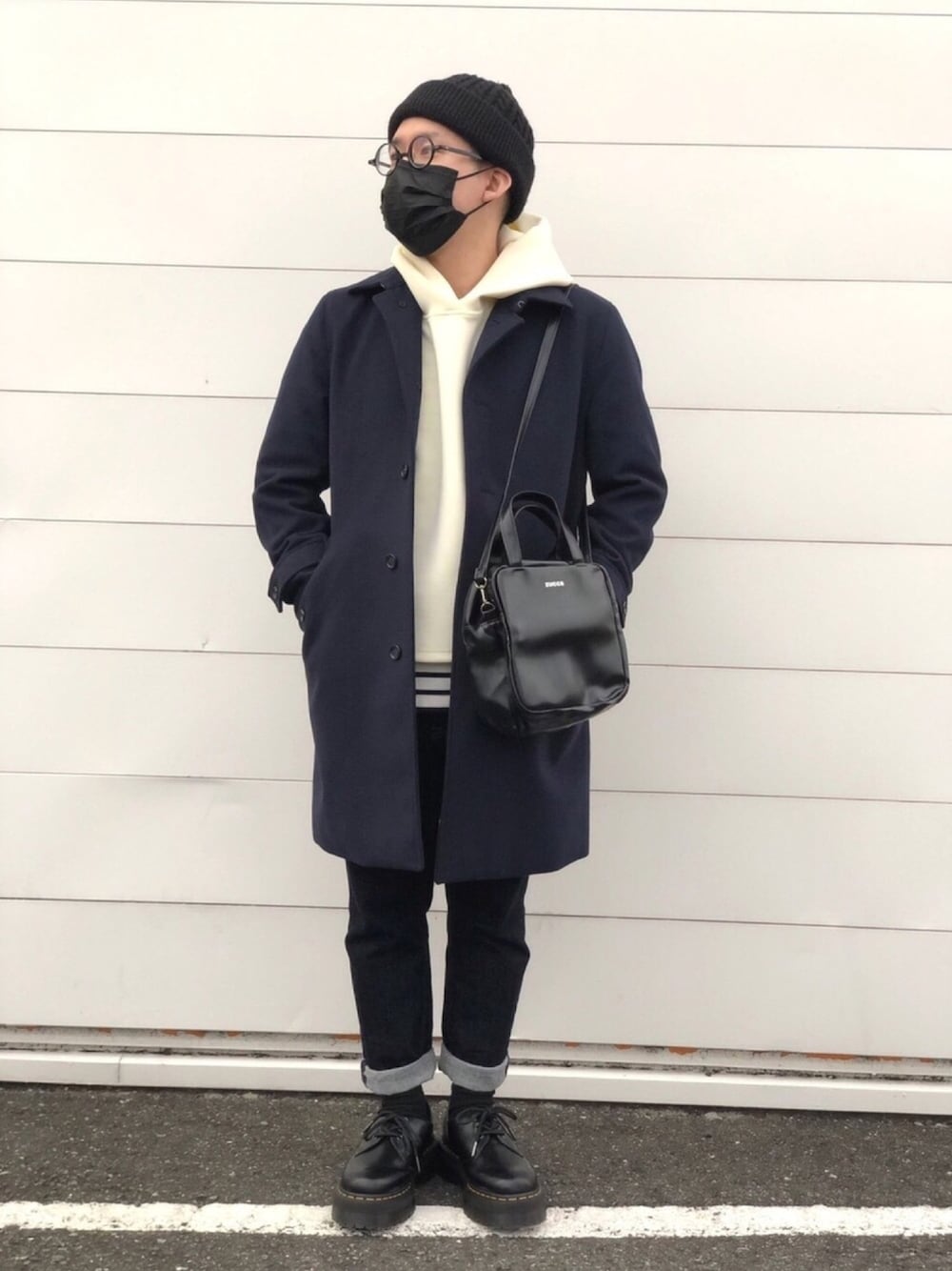 ブラック系のチェスターコート、ホワイト系のパーカー、ブラック系のバッグを着用したメンズの冬コーディネートの1枚目の写真