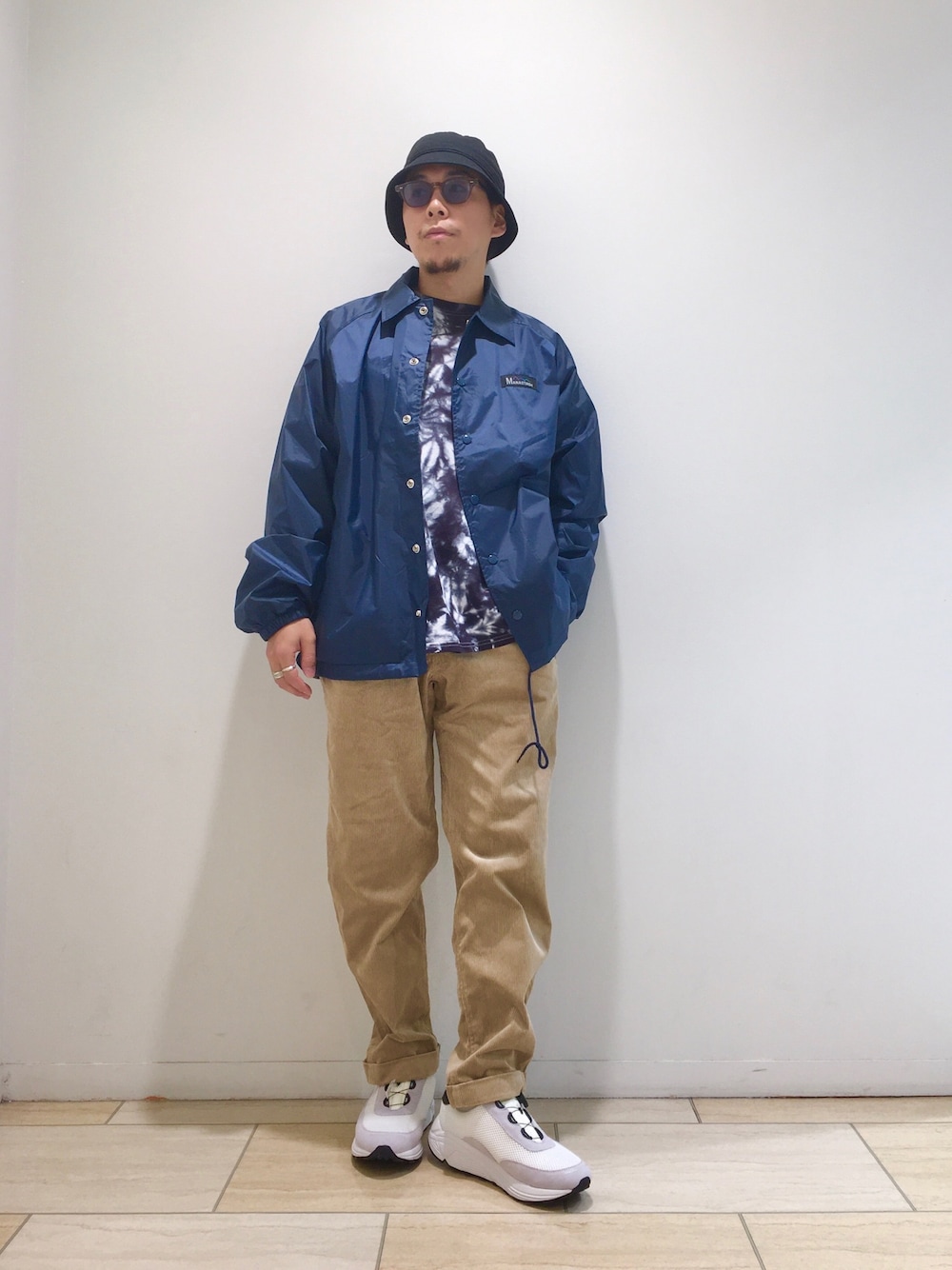 ブルー系のブルゾン、ブラック系のTシャツ/カットソー、ホワイト系のスニーカーを着用したメンズの秋コーディネートの1枚目の写真